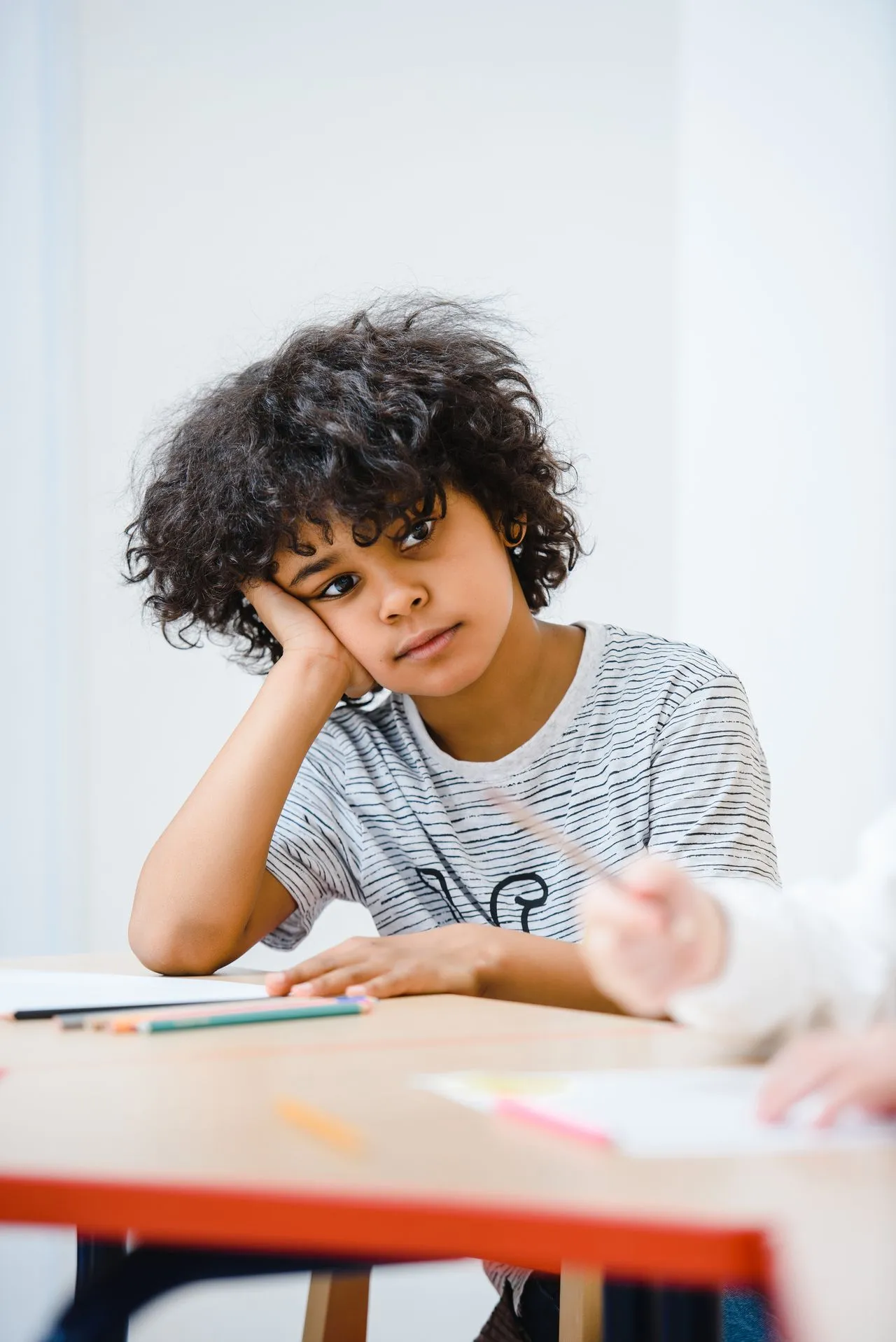 Child sitting at a desk looking distracted, representing attention challenges