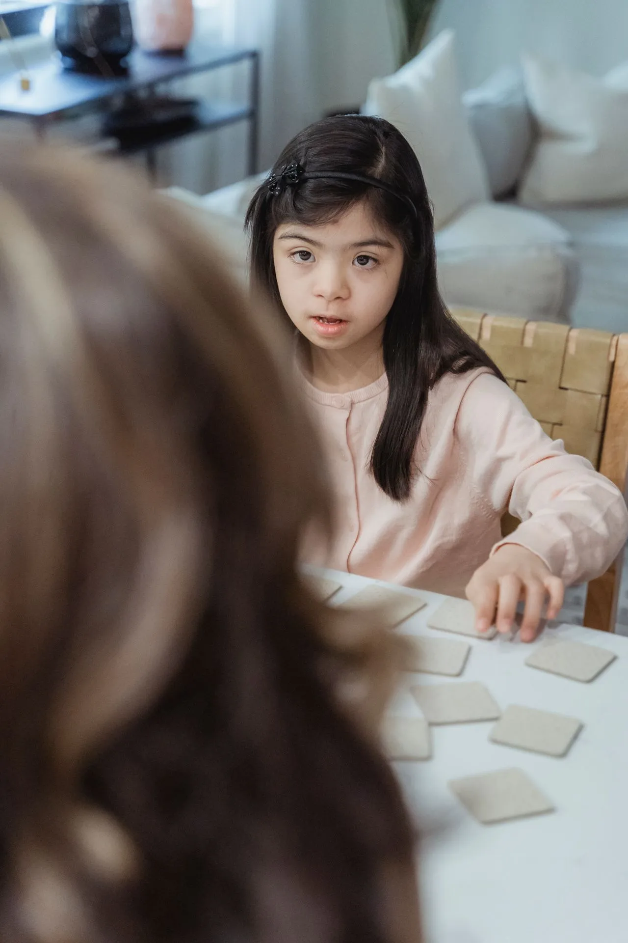A young child playing a memory matching game with an adult during an autism assessment